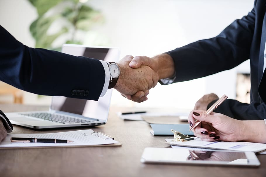 Two people shaking hands in an office after a successful referral